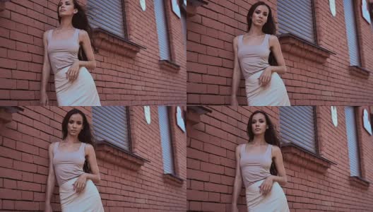 漂亮可爱的拉丁女人穿着衣服靠在一堵砖墙摆姿势高清在线视频素材下载