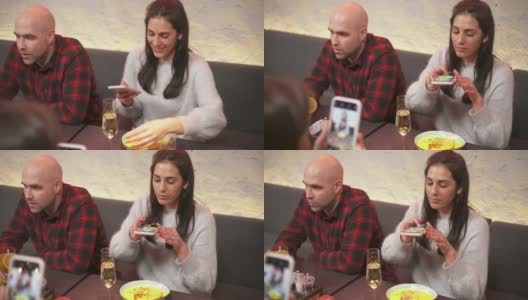 一名年轻女子在咖啡馆用智能手机拍食物照片，而她的朋友在给她拍照。朋友的陪伴是在一个美好的地方喝酒和享受时间。高清在线视频素材下载