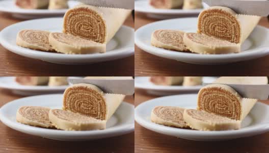 在切罗洛之火。将巴西甜点Bolo de Rolo(瑞士卷，卷饼)切成薄片，放在白色的盘子上，以木材为背景高清在线视频素材下载