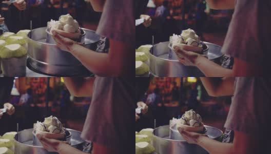 亚洲女游客在曼谷跳蚤市场享用椰子冰淇淋高清在线视频素材下载