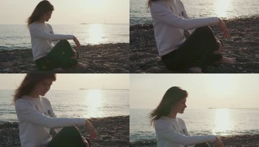 迷人的女孩独自坐在海滩上。高清在线视频素材下载