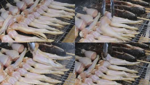 烹饪商人在炉子上用火烤鲜鸡翅，在火上冒烟。街上的泰国菜，视频片段1920x2080。手工烹饪的概念。高清在线视频素材下载