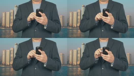 Business man using mobile phone on background modern skyscrapers高清在线视频素材下载