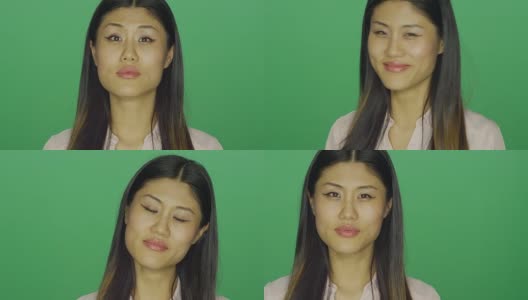 美丽的亚洲女人微笑，在一个绿色屏幕的工作室背景高清在线视频素材下载