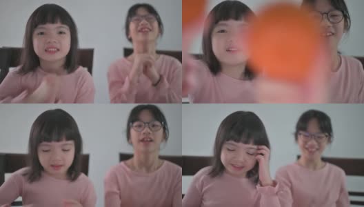 亚洲的中国小女孩和她的妹妹看着笔记本电脑的摄像头，用红包和橘子向她的祖父母祝贺春节高清在线视频素材下载