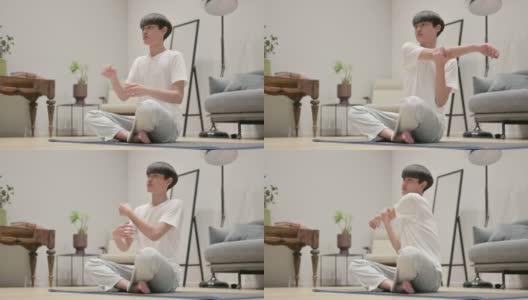 年轻的亚洲男子在瑜伽垫上做伸展运动在家高清在线视频素材下载