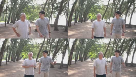夏日清晨，4K亚洲老人和成年儿子一起在海滩上做运动。高清在线视频素材下载