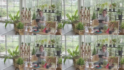 一名男子正在用平板电脑给自家花园里的植物拍照高清在线视频素材下载