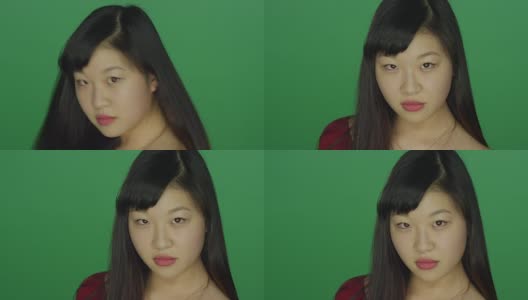 一名年轻的亚洲女子转过身来，盯着录音室背景的绿色屏幕上的摄像机高清在线视频素材下载