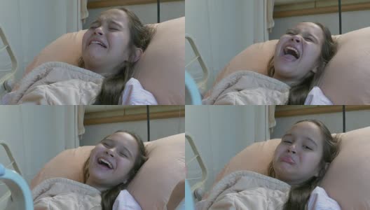 一个亚裔美国女孩躺在病床上，表现出疼痛，不安，尖叫，哭泣高清在线视频素材下载
