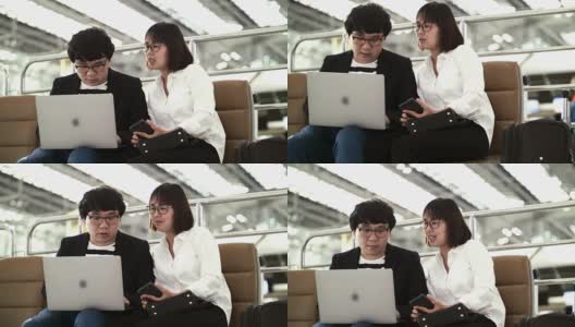 商人和女性在机场航站楼一起使用笔记本电脑高清在线视频素材下载