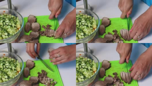 俄罗斯肉沙拉配蔬菜和蛋黄酱。一位妇女切下烤肉准备做沙拉。高清在线视频素材下载