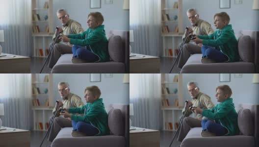 不满意的爷爷看着开心的孙子玩电子游戏的代沟高清在线视频素材下载