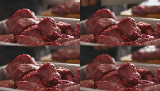 烹饪前，厨房里的红色生牛肉块。厨师在模糊的背景上切肉高清在线视频素材下载