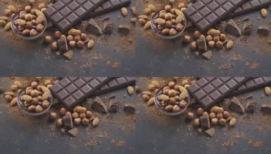 黑色背景上有杏仁和榛子的黑巧克力棒。制作巧克力的糕点厨师桌高清在线视频素材下载