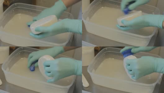 奶酪制作者的手用刷子和盐溶液刷了很多奶酪头高清在线视频素材下载